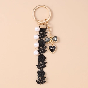 Detail of keychain with black lace flower, white pearls, and Love heart charm on gold ring