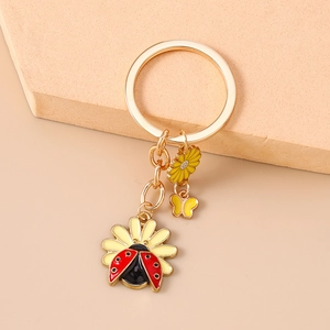 Detail of ladybug and daisy keychain with gold-plated charms and enamel finish