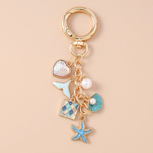 Detailed close-up of golden keychain with starfish, shell, pearl, and fish tail pendants