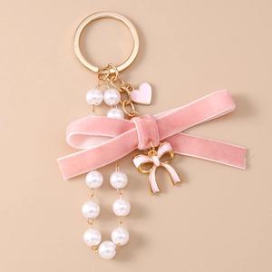 Detailed close-up of pink velvet bow keychain with pearls and heart enamel charms