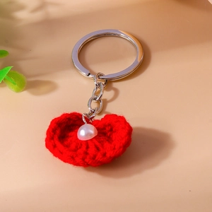 Nahaufnahme eines roten Strickherz-Schlüsselanhängers mit Perle und silbernem Ring