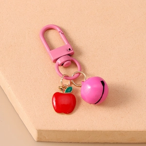 Close-up of pink lobster clasp with red apple charm and matching jingle bell keychain