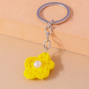 Close-up of handmade yellow crochet flower keychain with pearl and silver ring