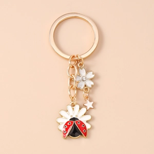 Detailed macro view of golden keychain with enamel daisy, ladybug and sakura flower charms