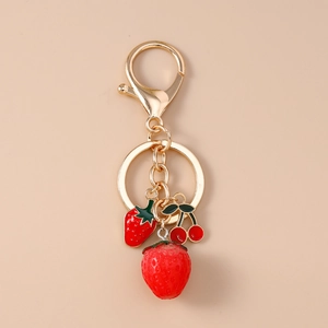 Detail of fruit keychain featuring enamel strawberry, cherry charms, and gold lobster clasp