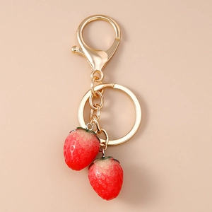 Macro detail of realistic red strawberry charms and gold lobster clasp keychain