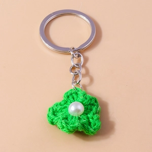 Macro detail of handmade crochet green flower keychain with pearl and silver metal ring
