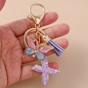 Dettaglio portachiavi a farfalla viola con lettera X glitterata e nappa in pelle