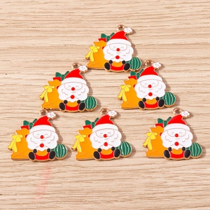 Detail von sechs Emaille-Weihnachtsmann-Anhängern mit gelbem Geschenksack auf Holz
