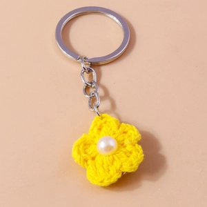 Detailed close-up of handmade yellow crochet flower keychain with white pearl bead