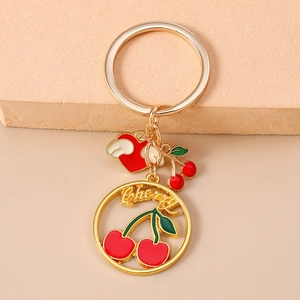 Portachiavi a ciliegia dorato alla moda con cuore alato rosso e ciondolo a ciliegia