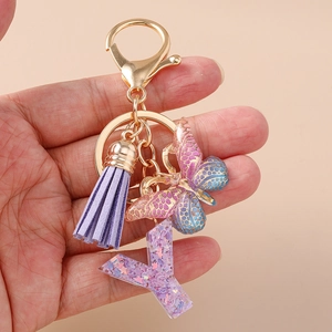 Dettaglio di un portachiavi alla moda con nappa viola, farfalla e lettera Y in resina