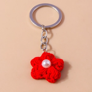 Detail of red crochet flower keychain with pearl center and silver metal keyring