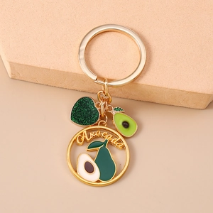 Dettaglio ravvicinato di un portachiavi a cuore avocado dorato con glitter verdi e ciondoli