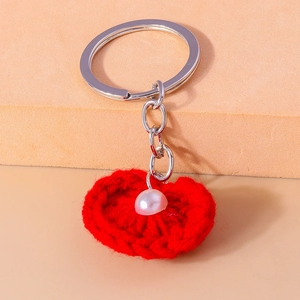 Nahaufnahme von handgestricktem rotem Herz-Schlüsselanhänger mit weißer Perle