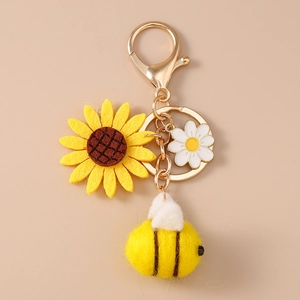 Dettaglio del portachiavi in peluche girasole e ape con margherita e anelli dorati