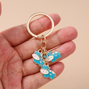 Cute golden cow keychain with blue enamel animal charms held in hand for bag decor