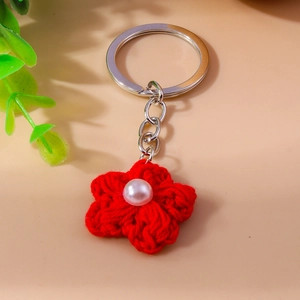 Detail of red knitted flower keychain with a white pearl and silver metal ring