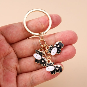 Detail of cute cow charms with enamel coating on a golden metal keychain ring