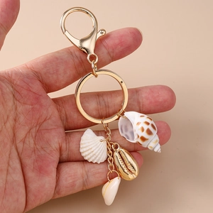 Détail d'un porte-clés doré orné de divers coquillages et de pendentifs marins variés