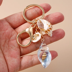 Detailed close-up of handmade shell keychain with leopard conch held in hand
