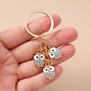 Détails de porte-clés hibou doré montrant l'artisanat en émail et les anneaux métalliques