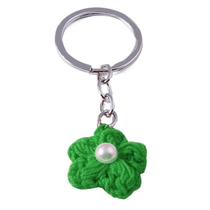 Macro detail of hand-knitted green flower keychain with white pearl center and metal ring