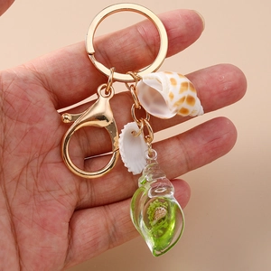 Close-up of beach shell keychain with natural conch and green resin pendants