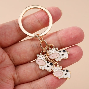 Cute cartoon cow keychain with gold alloy rings and three black and white spotted pendants