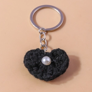 Detail eines schwarzen gehäkelten Herz-Schlüsselanhängers mit Perle und silbernem Ring