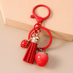Detailed view of red strawberry keychain with microfiber tassel and metal fruit charms