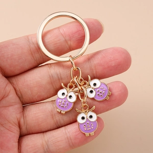 Vue détaillée des pendentifs chouettes en émail violet sur un porte-clés doré