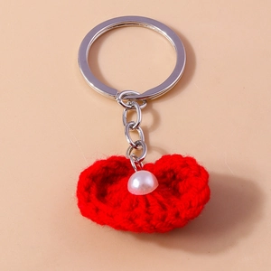 Detail eines roten gestrickten Herz-Schlüsselanhängers mit Perle und Metallring