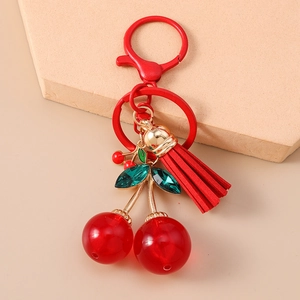 Detailed view of creative cherry keychain with red tassel and green gemstone leaf details