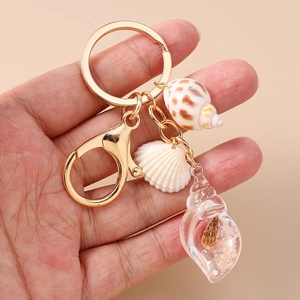 Close-up of summer shell keychain with resin conch and natural seashells held in hand