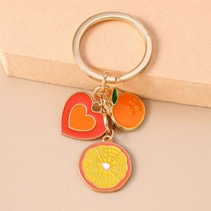 Fashion fruit keychain with enamel heart and orange charms on a warm beige background