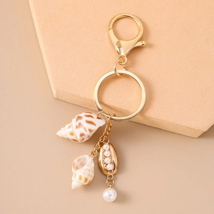 Détail du porte-clés de plage avec coquillages, perles et étoile de mer sur anneaux dorés