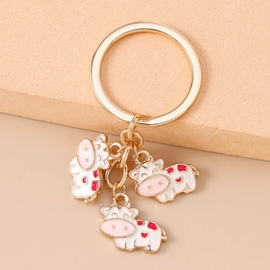 Detail of cartoon cow keyrings with gold-tone rings and colorful enamel charms