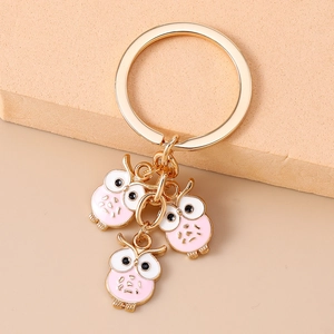Détail de pendentifs chouettes dorés avec émail rose sur un porte-clés élégant