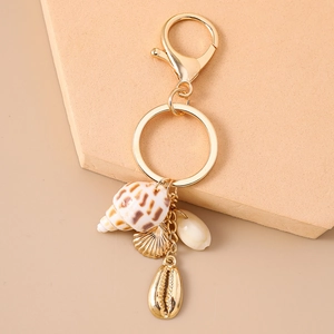 Détails de pendentifs en coquillage doré et conque naturelle sur un porte-clés de plage