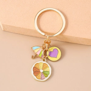 Detail of colorful enamel orange slice and rainbow umbrella charms on gold keychain