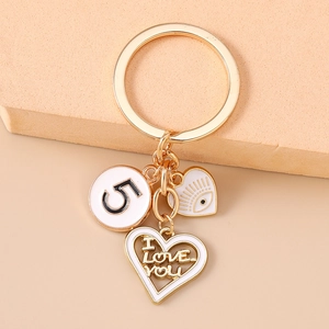 Golden keychain with evil eye heart and I LOVE YOU engraving on a soft pink surface