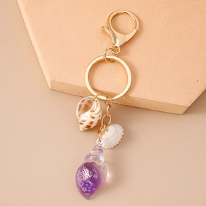 Detail view of gold shell keychain with purple resin conch and floral butterfly patterns