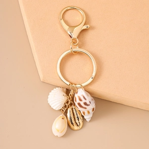 Détail d'un porte-clés doré avec des pendentifs de coquillages et d'étoiles de mer sur un socle