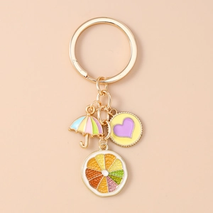 Detail of creative gold metal keychain with colorful umbrella heart and orange enamel charms