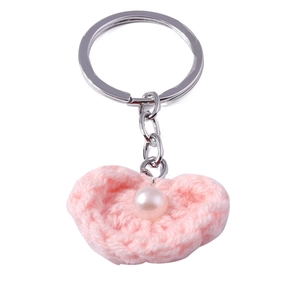 Detail eines rosa gehäkelten Herz-Schlüsselanhängers mit Perle und Silberring