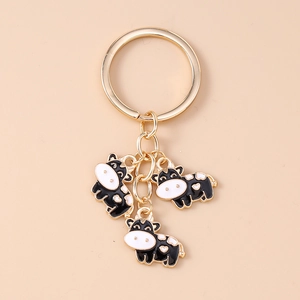 Detail of cute cartoon cow keychain charms with enamel finish and gold key ring