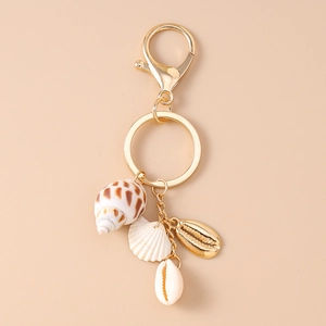 Détail d'un porte-clés étoile de mer doré avec coquillages naturels et fermoir mousqueton
