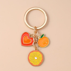 Detail of creative orange and heart enamel charms on a golden metal keychain