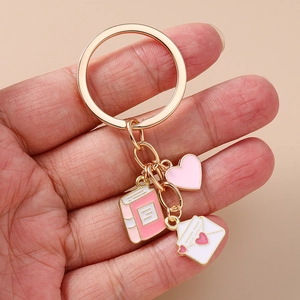 Fashionable gold-plated keychain featuring pink book, heart, and envelope charms